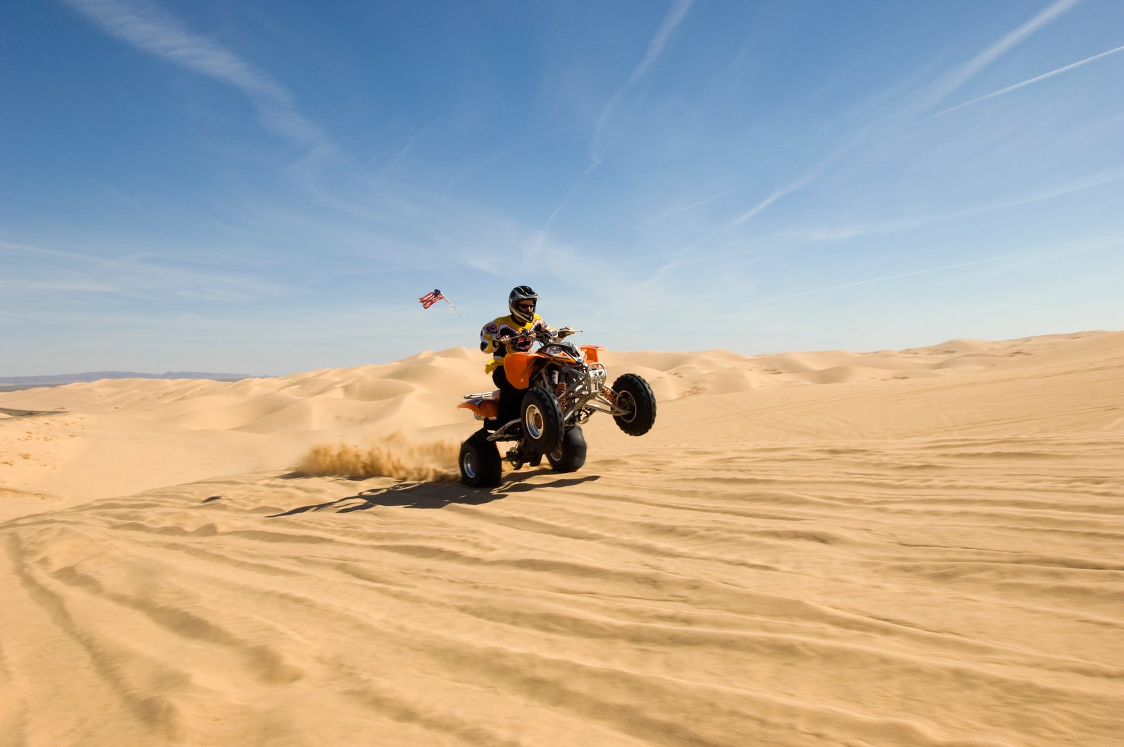 Young quad bike rider doing wheelie in desert