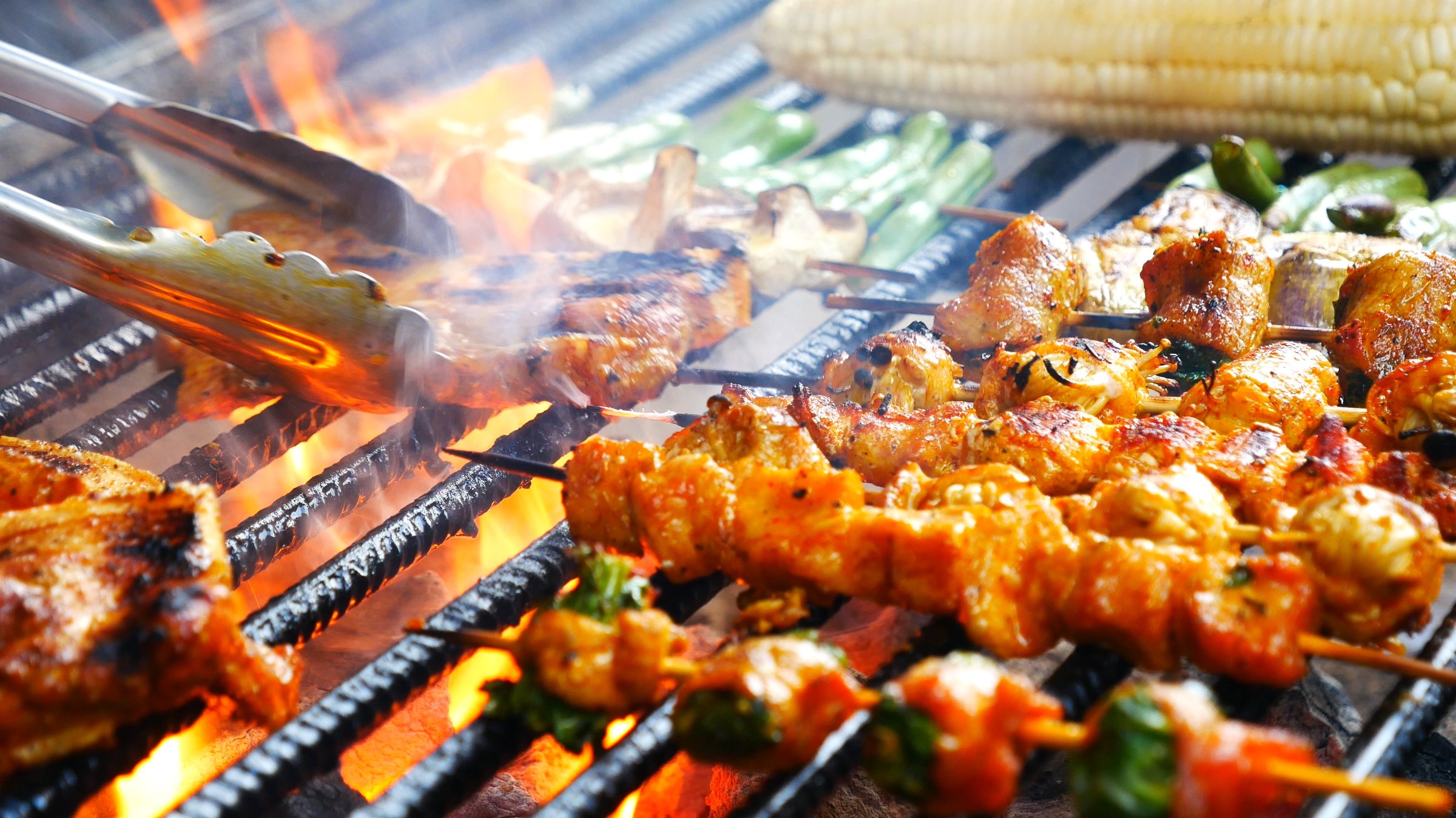 BBQ Barbecue grilled meat stick on fire flame with hot charcoal cooking outside. Beef grilling picnic outdoor with smoke bacon spicy sausage for party. Grill pork bbq on fire flame