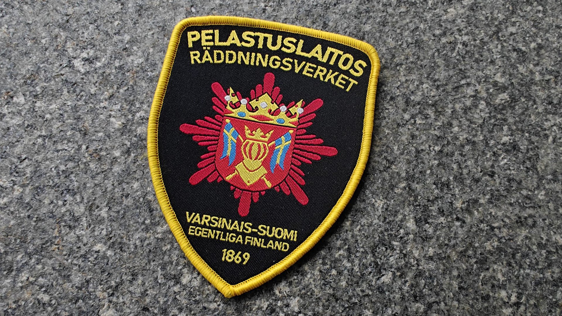 A patch for the Varsinais-Suomi rescue service, featuring a crest with a crown, text in Finnish and Swedish, dated 1869.