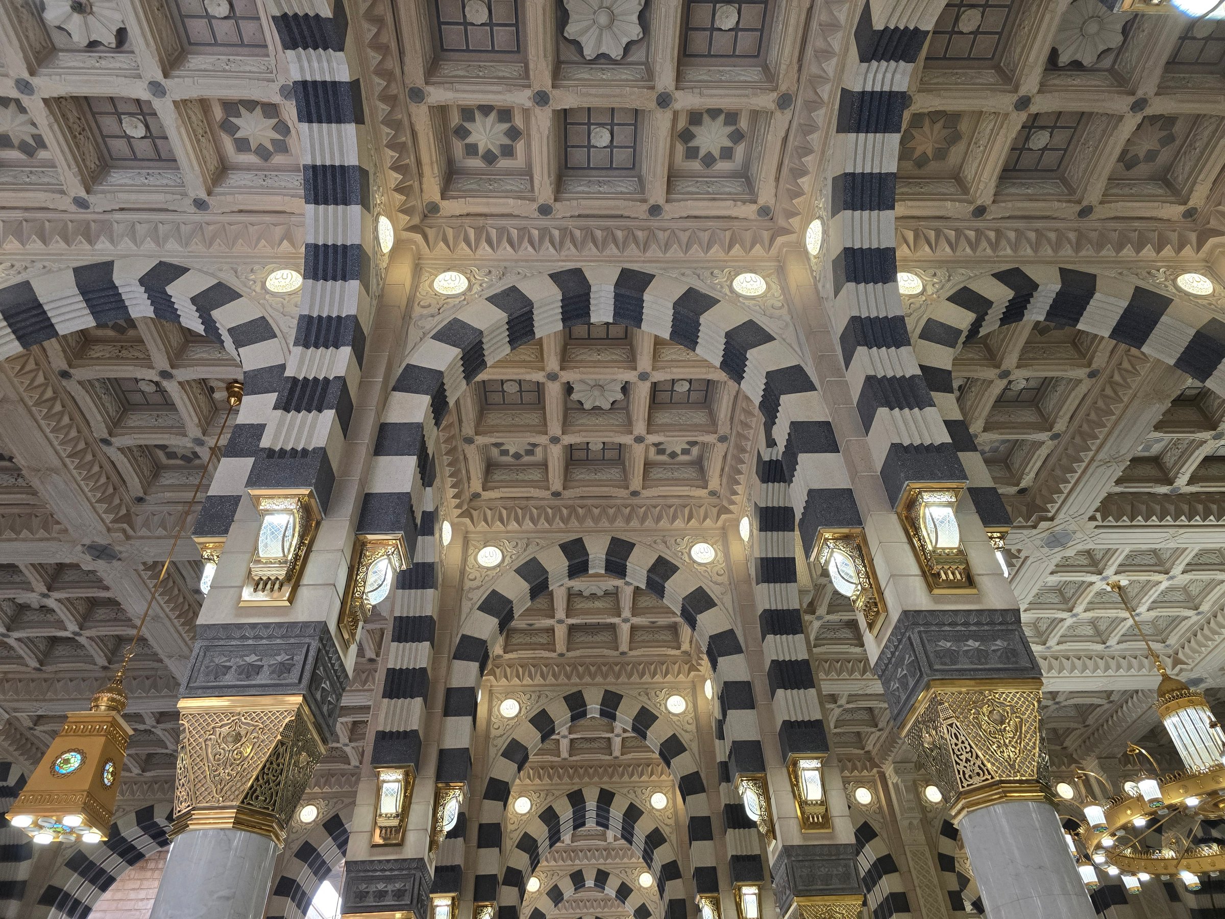 The image describes the interior detailing of pattern and ornament inside Nabawi mosque and also the praying activities in there.