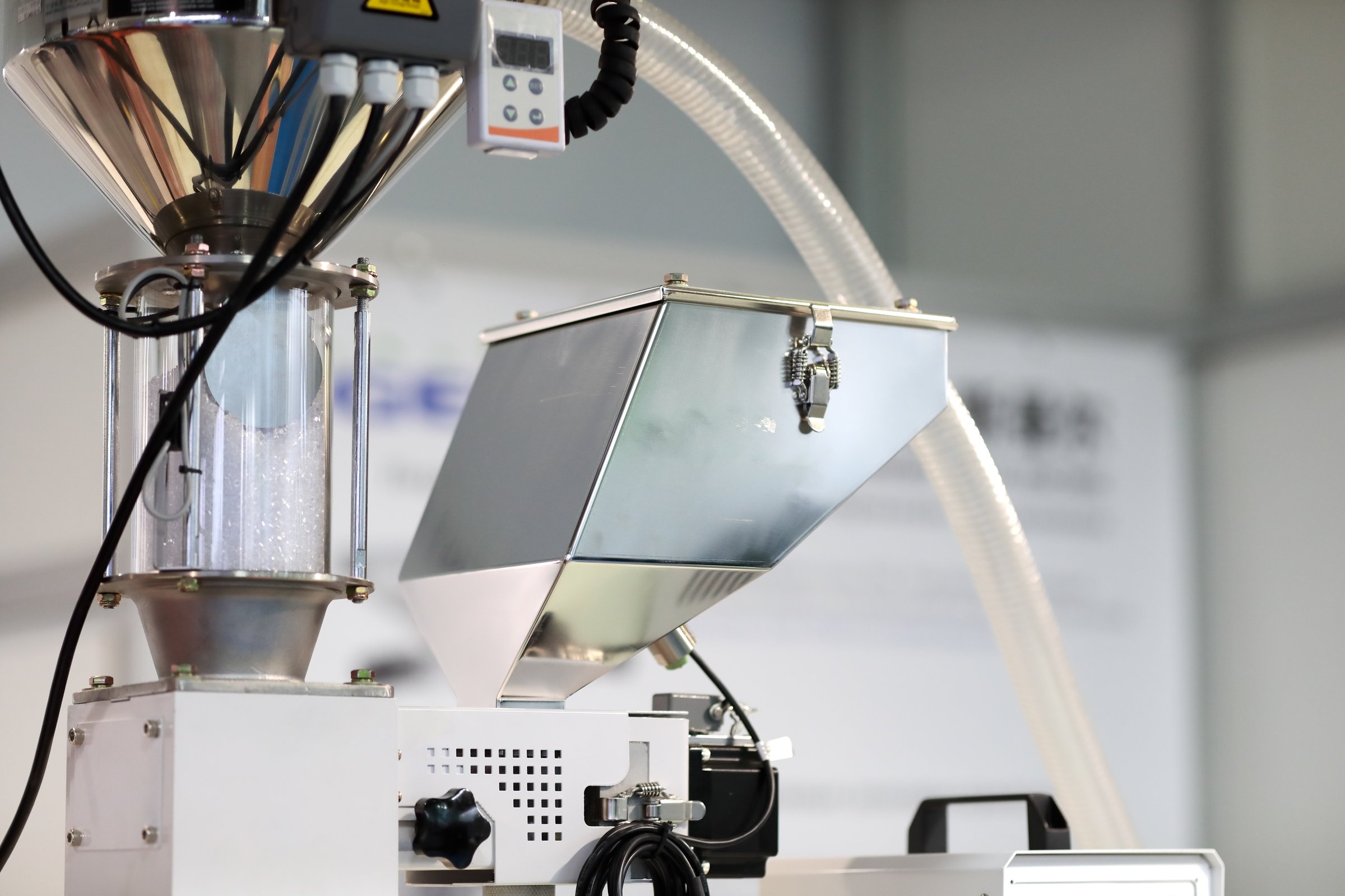 Feed hopper with raw plastic granules and single color dose mixer. Parts  of plastic injection molding machine. Selective focus.