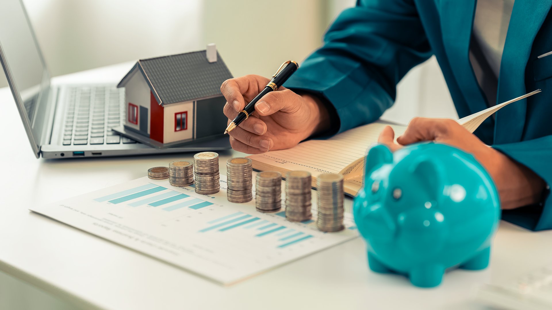 Businessman with pile of coins and piggy bank doing financial accounting for loan, investment using calculator and pile of coins. Money saving concept.