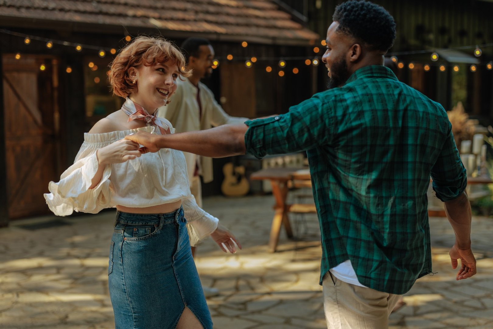 Happy young multi-ethnic couple holding hands and dancing together at an outdoor country party