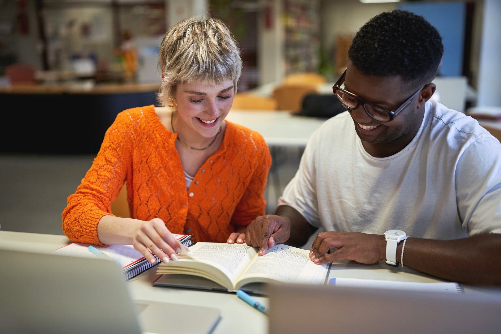 Smiling university students studying together in library