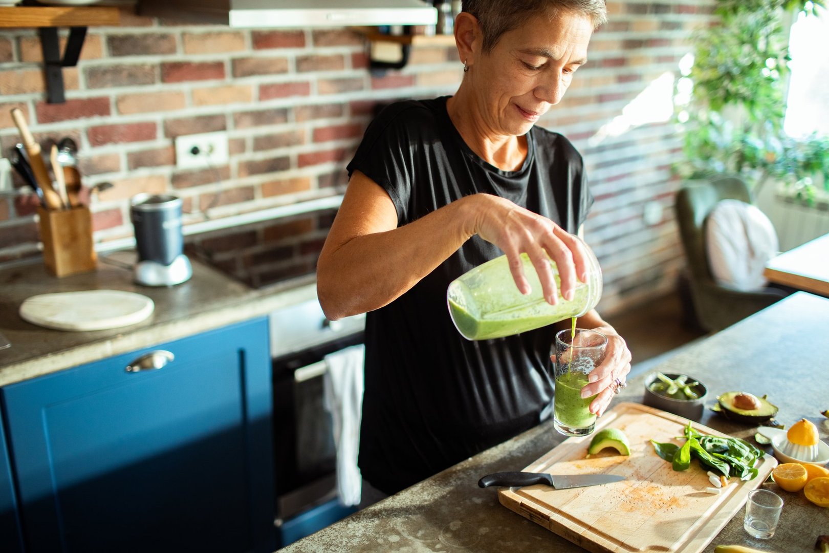 Close up of a Mature woman preparing a healthy smoothie in the kitchen at home