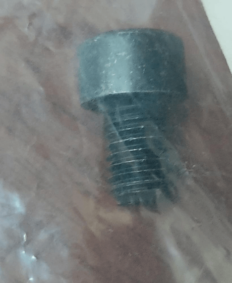 Close-up of a metal hexagonal bolt head with visible threads, placed on a flat surface possibly covered in plastic.