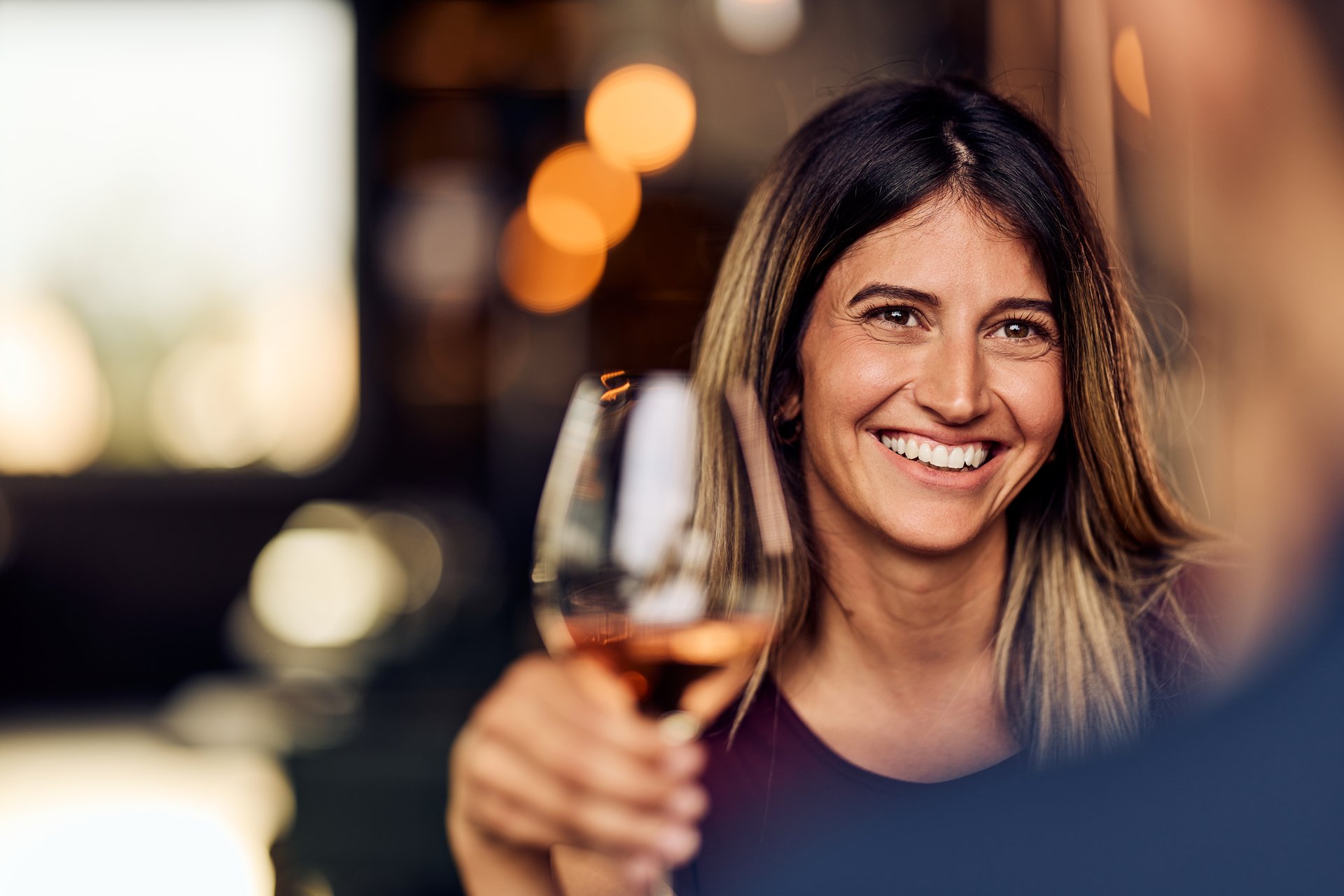 A happy woman shares a joyful moment while holding a wine glass.
