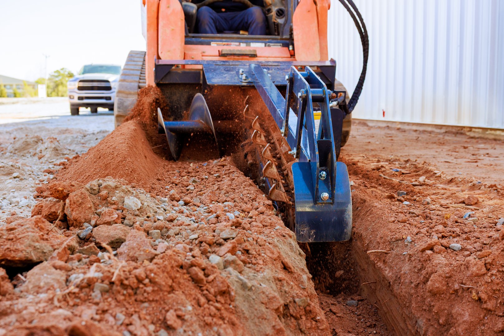 Worker operates trencher to dig trench in ground for construction purposes