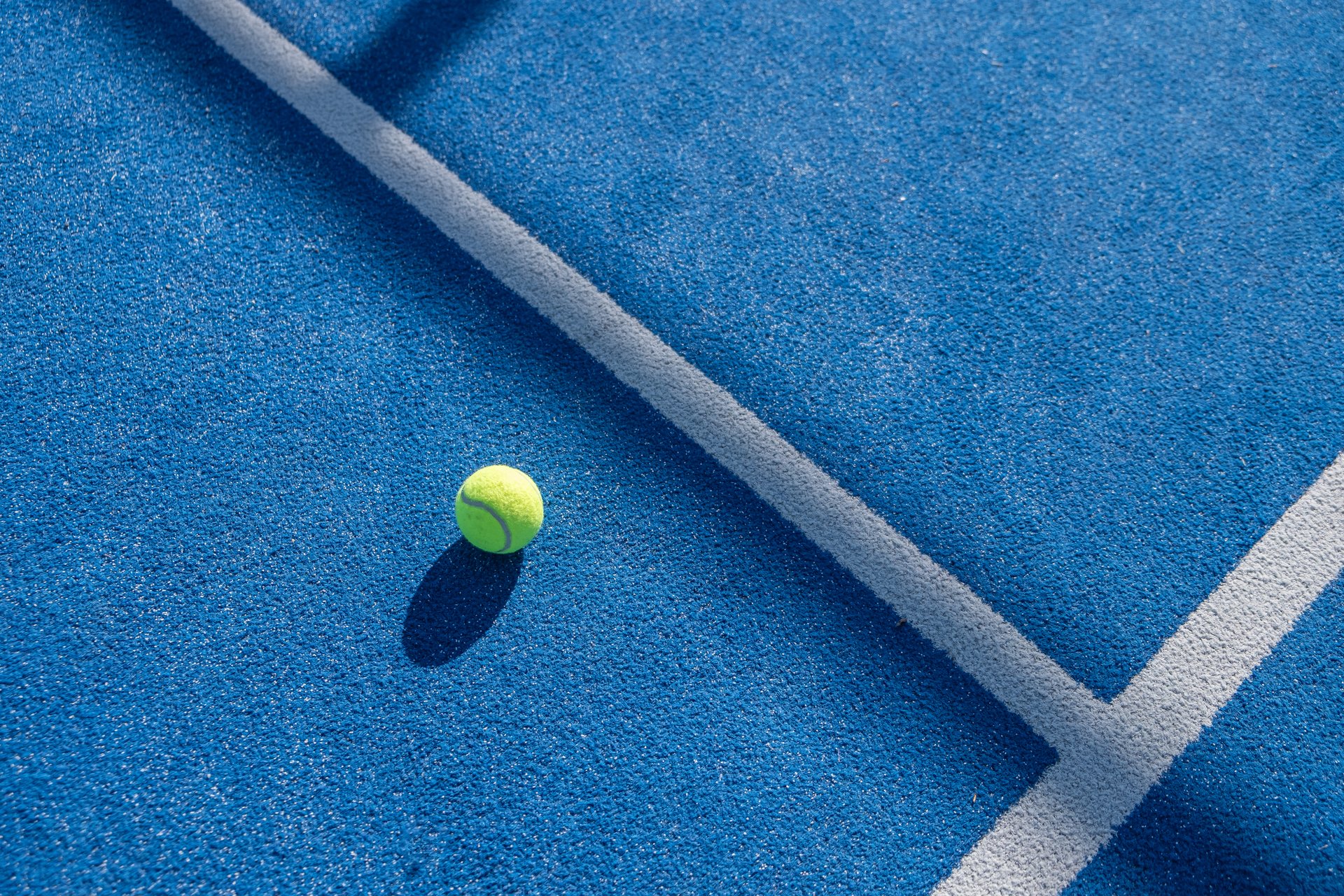 yellow paddle tennis ball on blue turf court