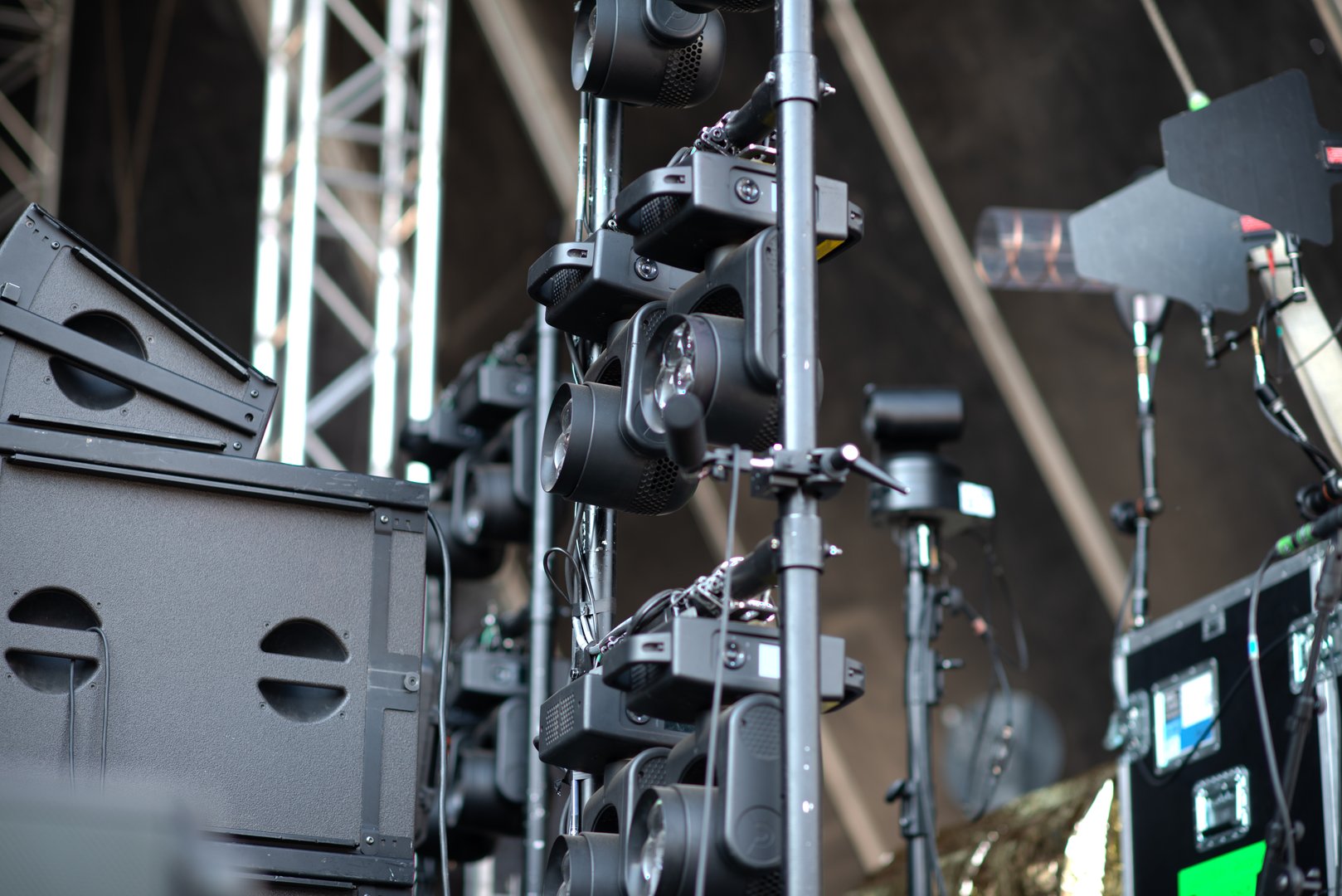 Professional stage lighting fixtures, stacked speakers, and sound equipment mounted on truss rigging, prepared for concert or live event production.