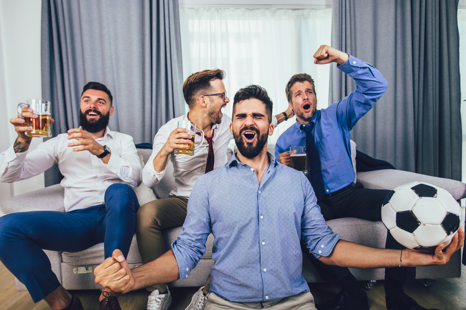 Group of football fans watching soccer game on television and celebrating goal.