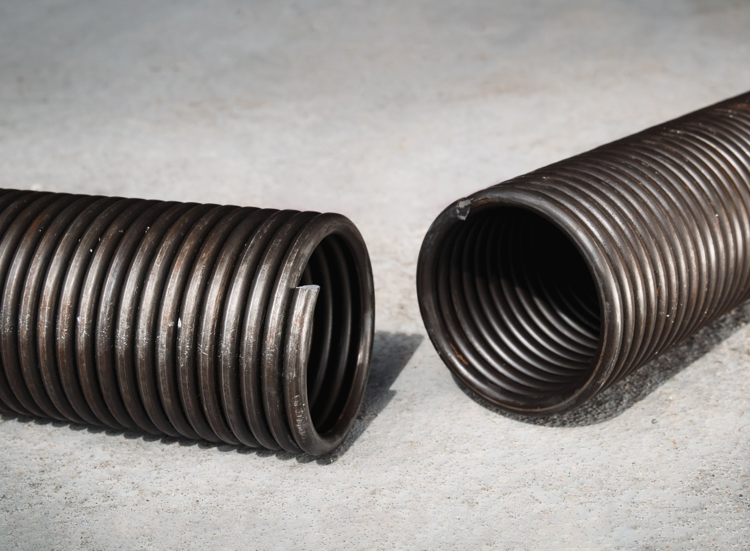 Sheared-off spring from a garage gate mechanism. Material failure. Large coil snapped apart. Selective focus.