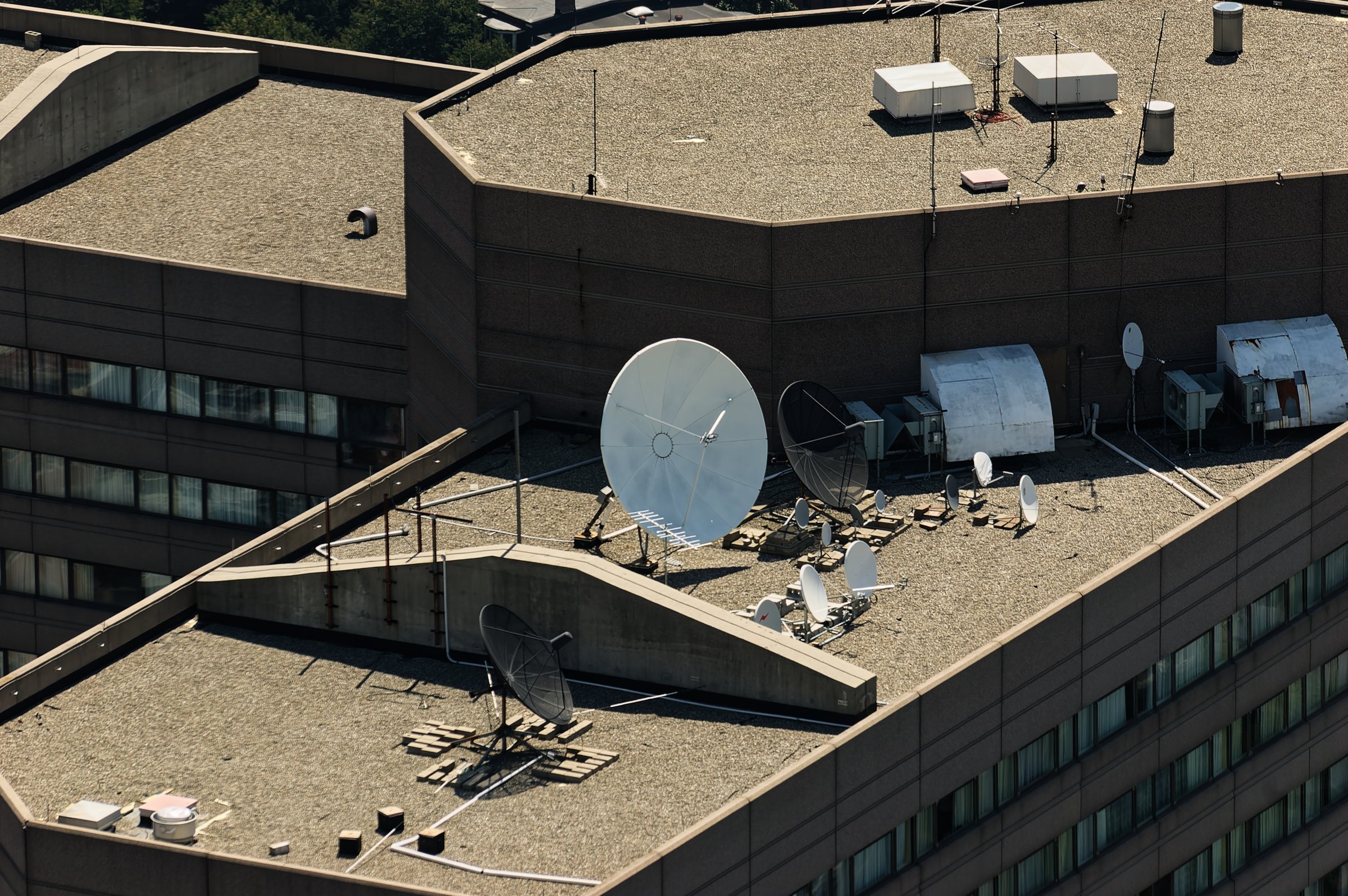 Satellite dishes on urban rooftop under clear sunny sky
