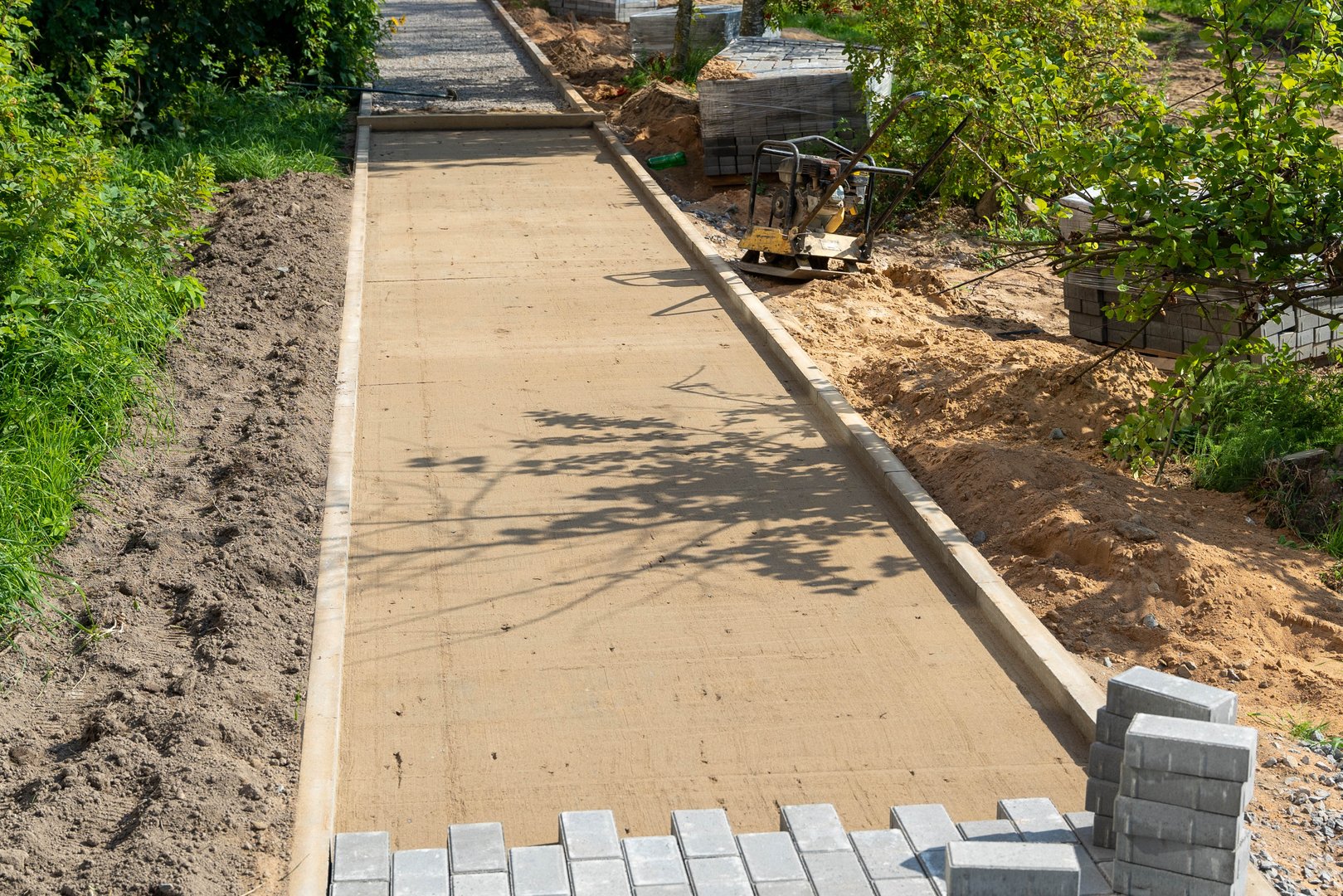 Workers progress on laying a new pathway in a garden area.