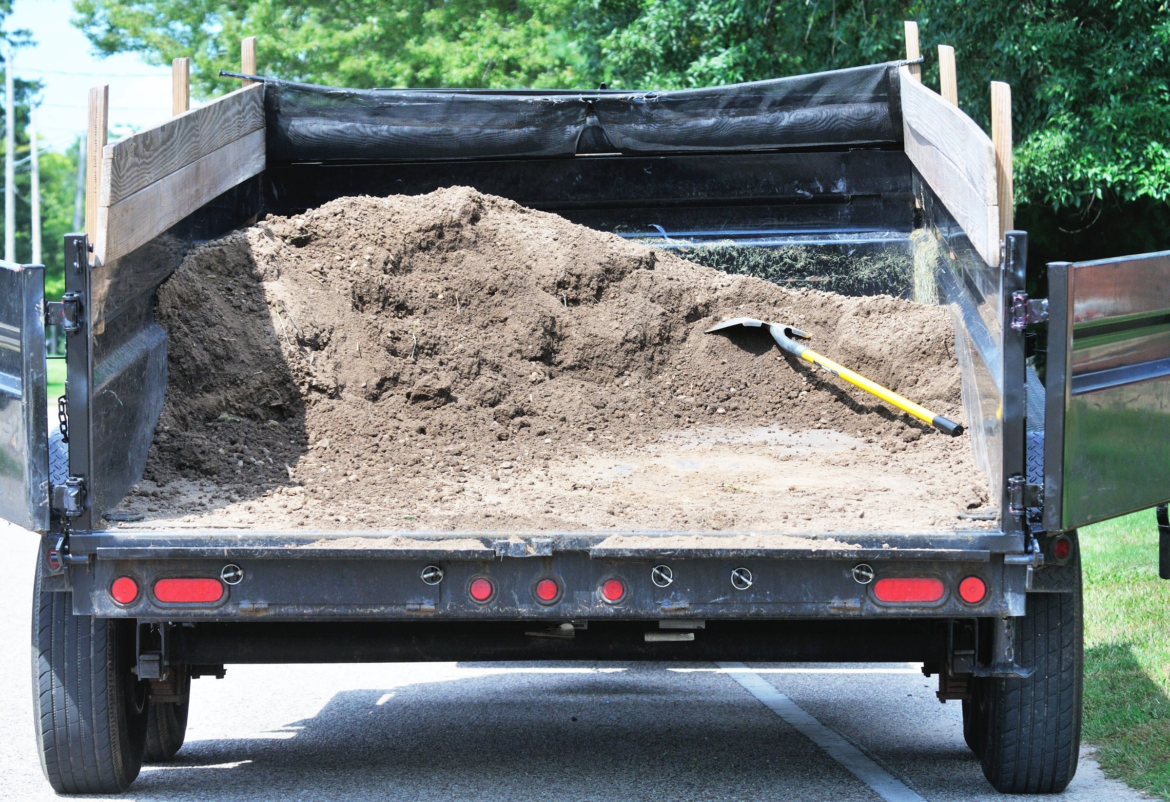 Load of dirt with shovel in wagon or truck.