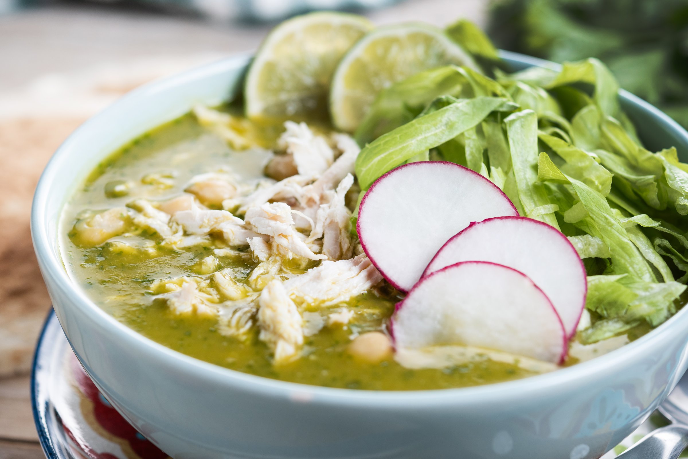 Traditional mexican green pozole soup on wooden table