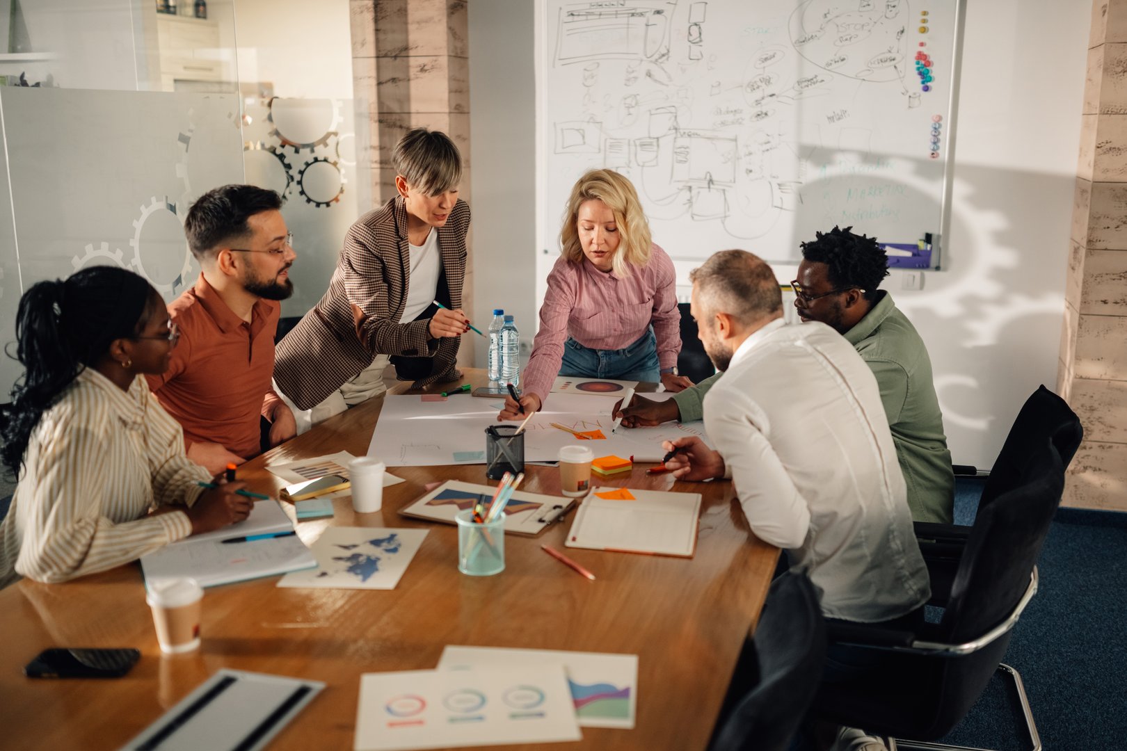 Diverse team of marketing professionals working together on a project in a modern office, analyzing charts and graphs on a large table