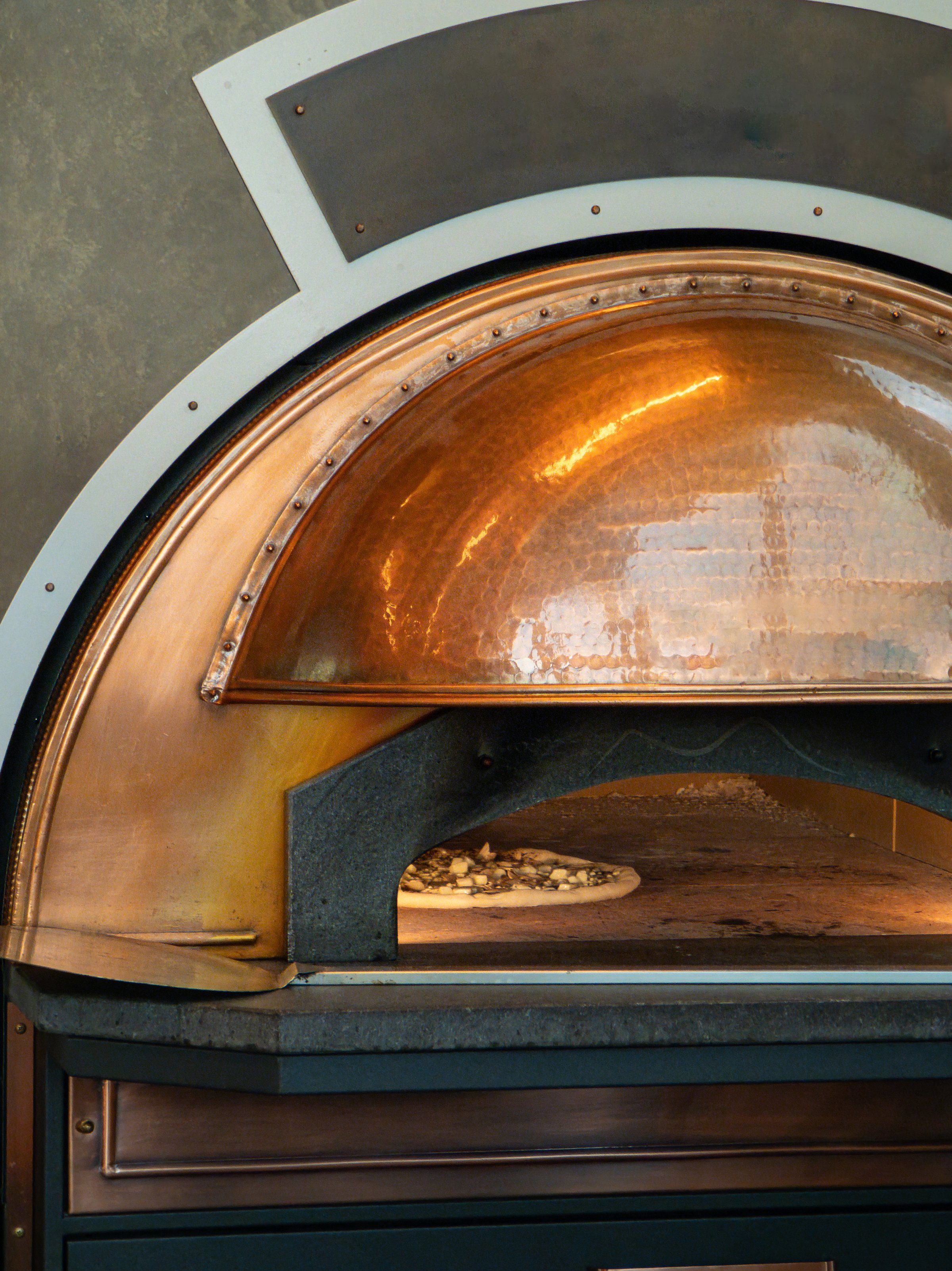 Pizza making in a vintage-style copper oven