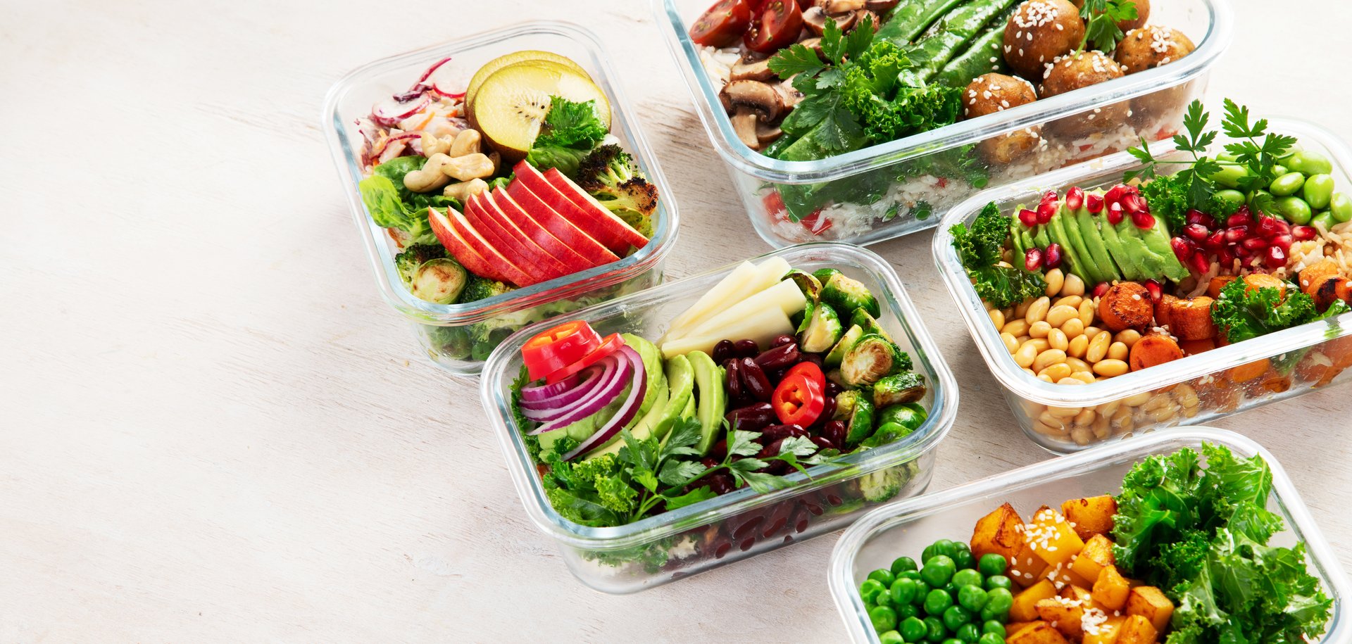 Preparing healthy meals for vegans. Food and snacks in containers on a light background. Top view. Panorama with copy space.