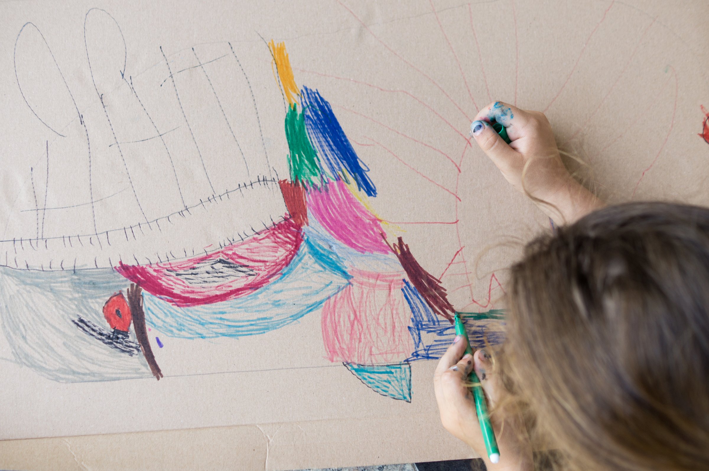 Selective focus of an unrecognizable child drawn with a colored marker