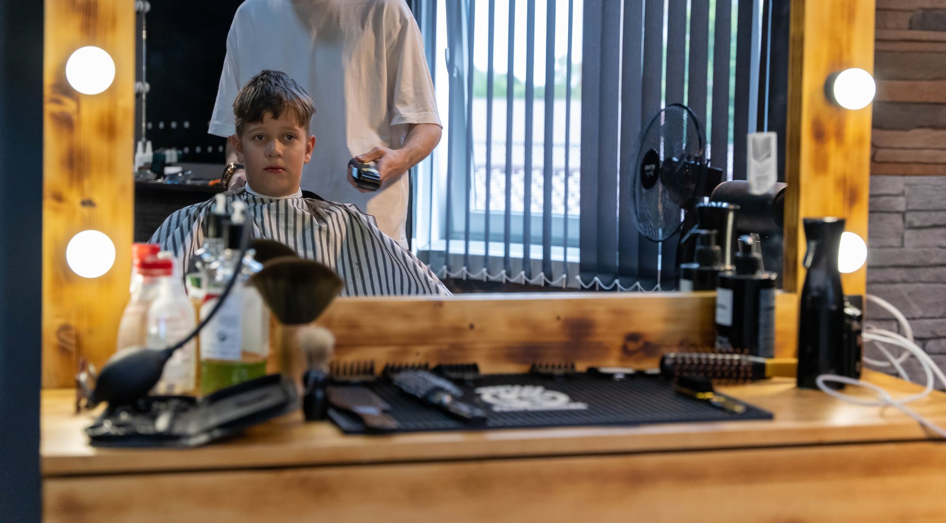 A young boy sits in a barber chair, getting a haircut