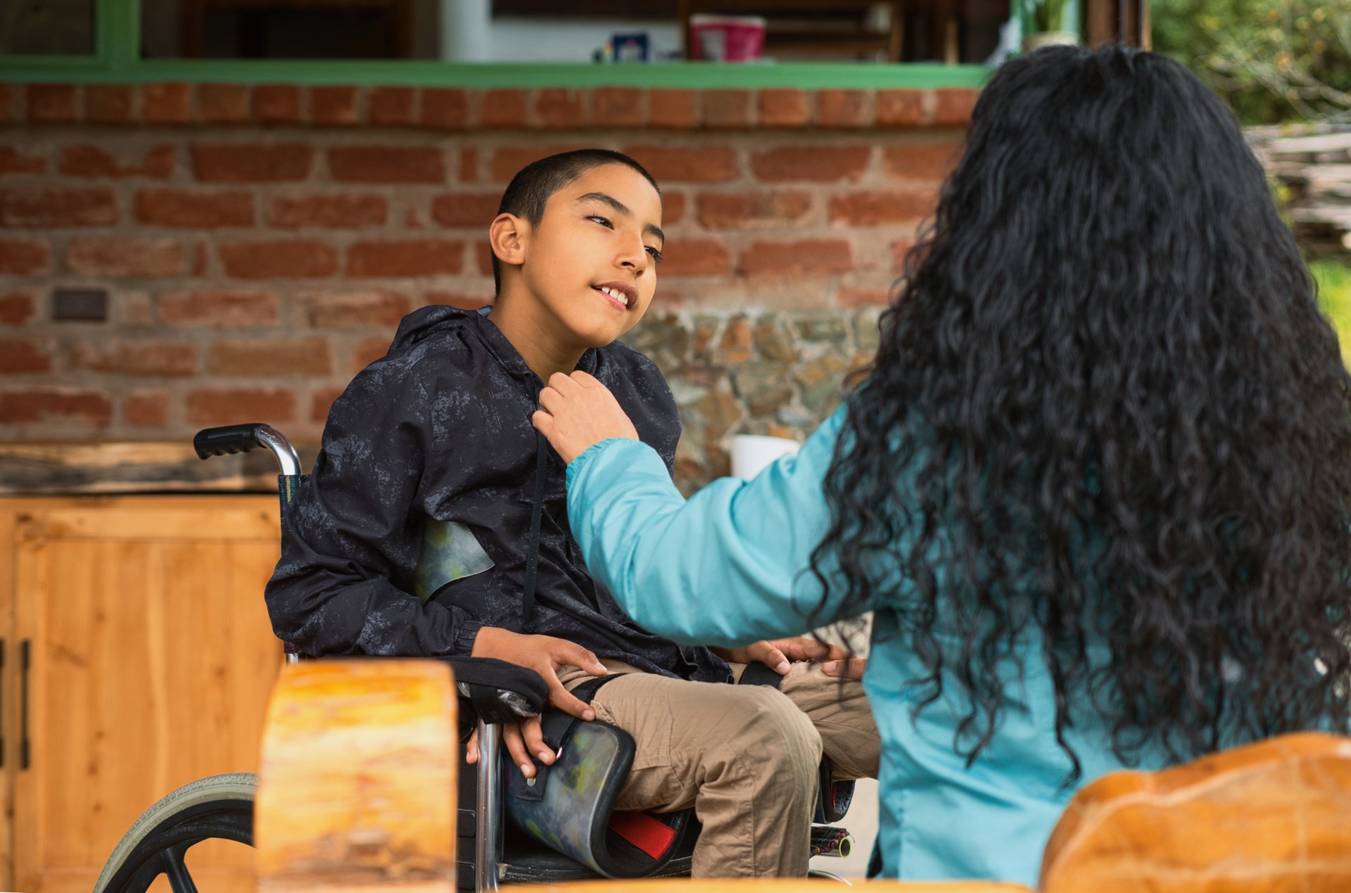 Caregiver assisting a child in a wheelchair outside a rustic building, highlighting compassion and accessibility while promoting inclusive travel experiences for everyone