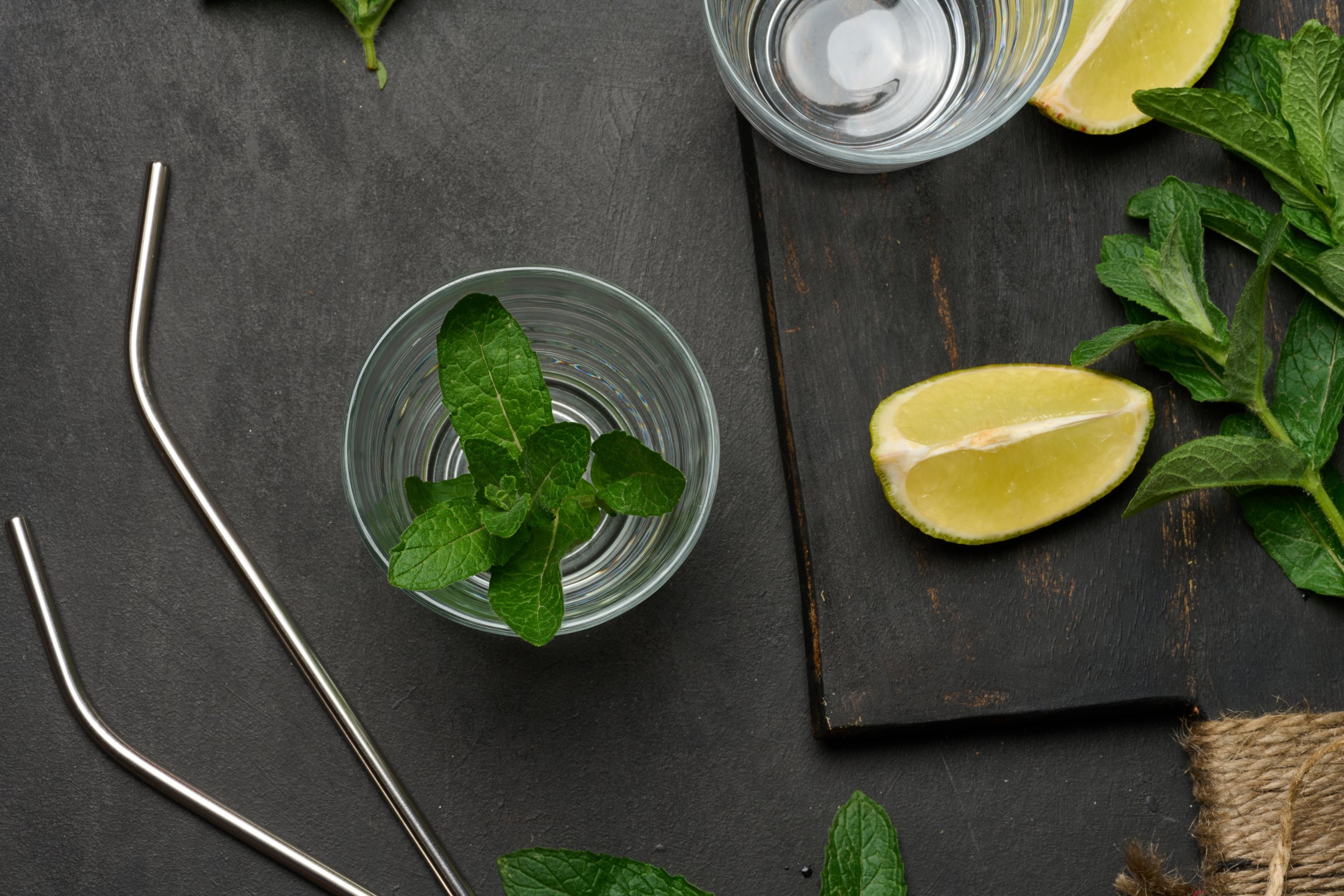 Bunch of fresh green mint, lime slices, glasses, top view. Cocktail ingredient