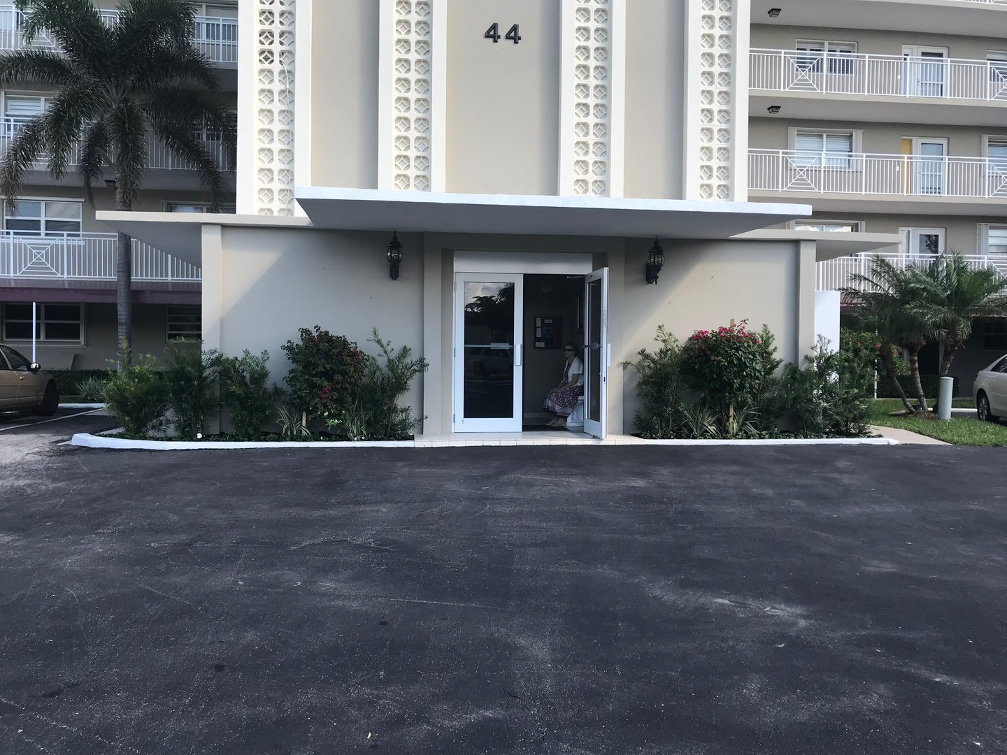 Entrance to a multi-story building with plants on either side of the door. Number 44 is displayed above the entrance.