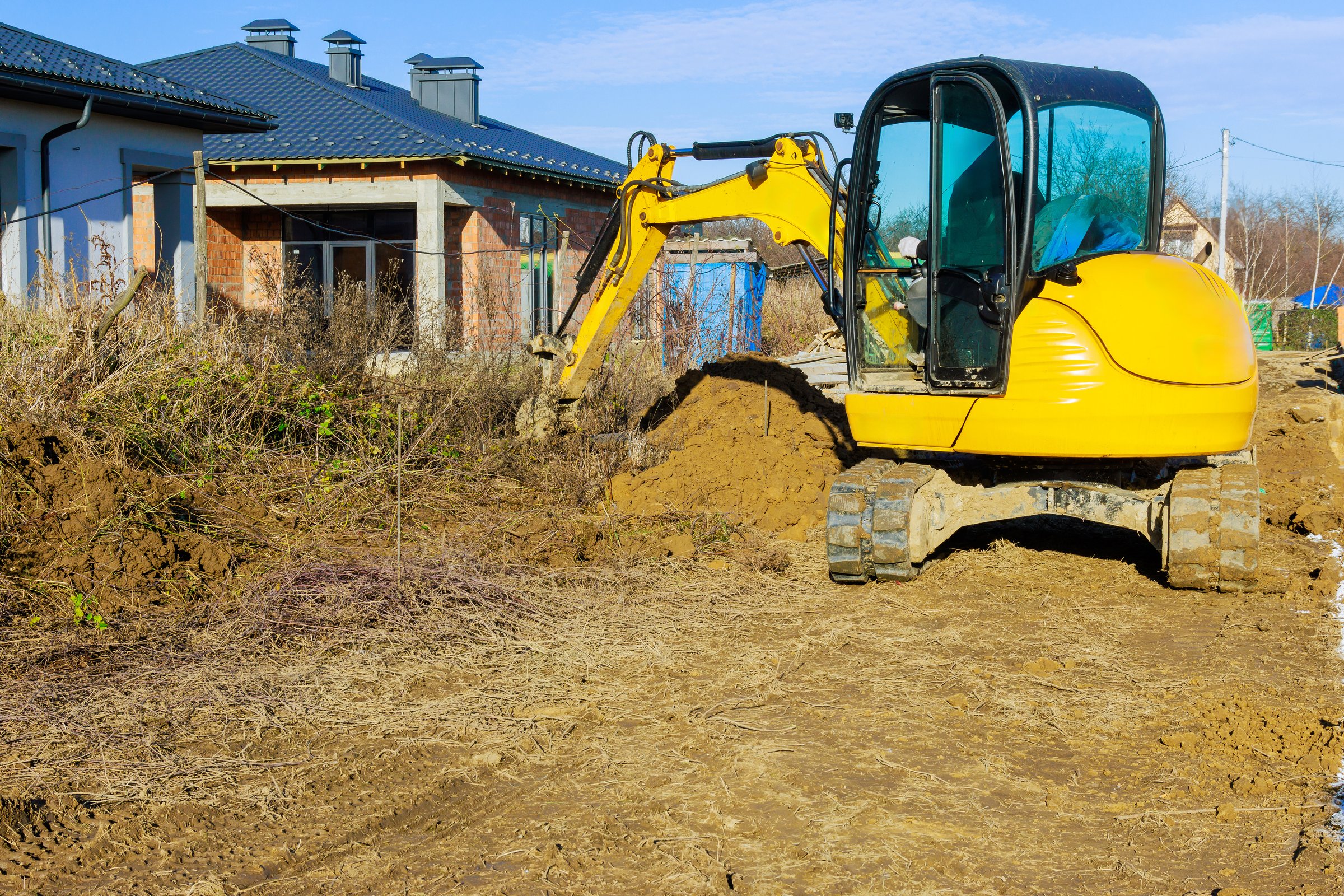 Heavy bulldozer digs at construction site where new house is being built