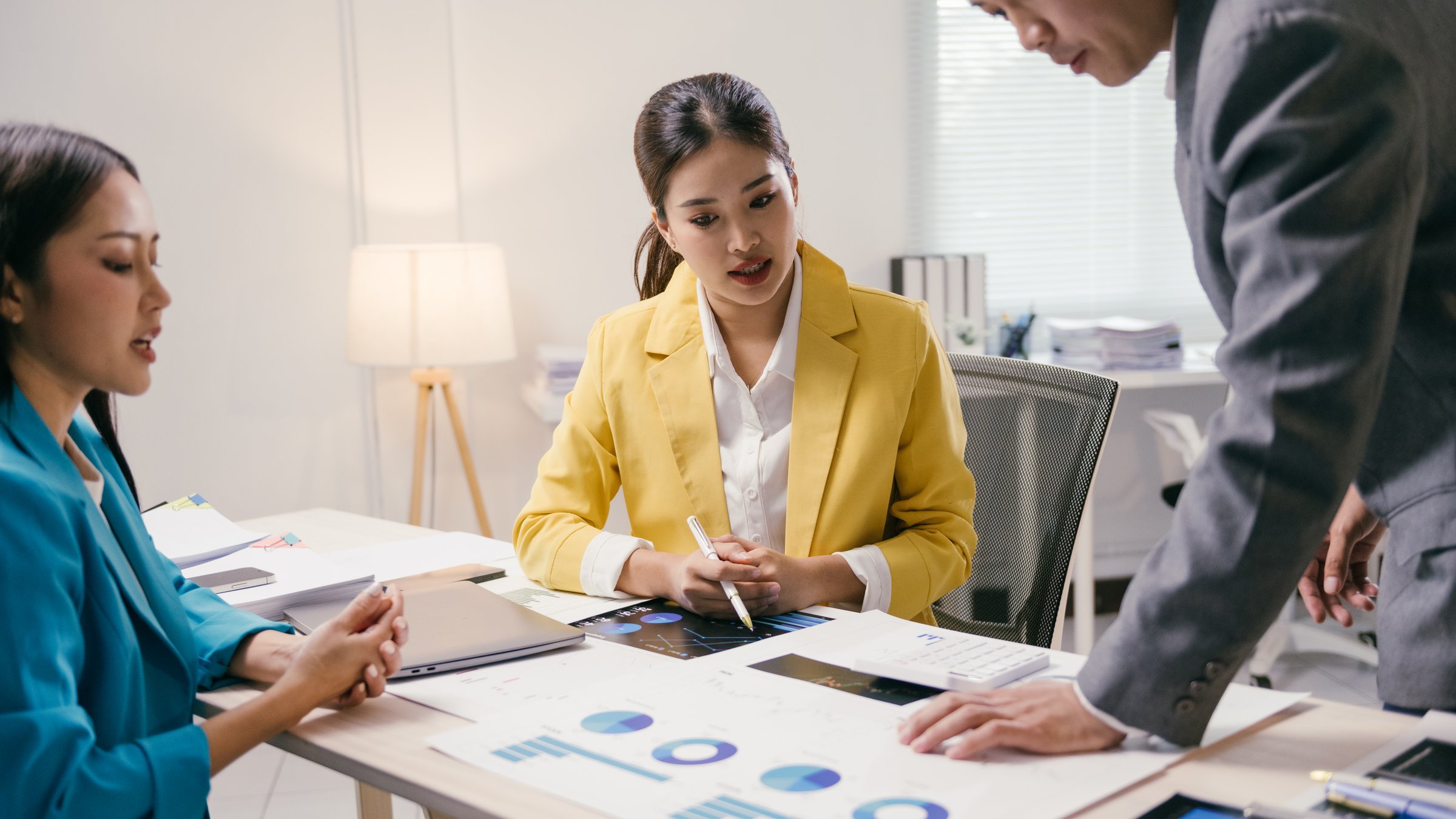 Asian business team analyzing financial charts and reports during a productive meeting in a modern office, discussing strategies and making informed decisions