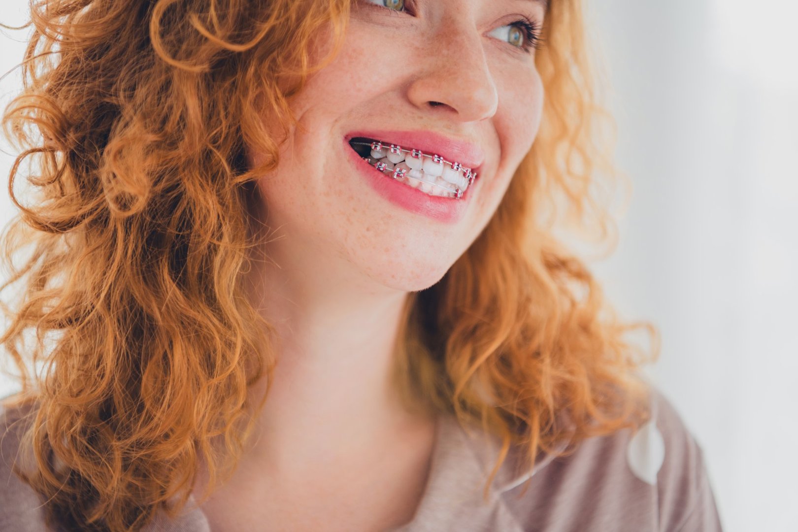 Young red-haired woman with braces smiles joyfully