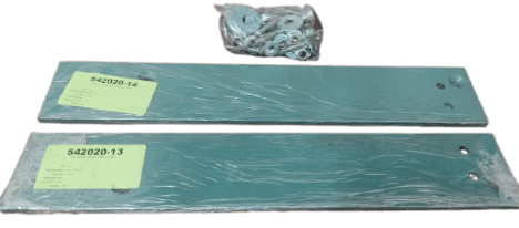Two green metal plates with labels and packaged parts, possibly washers, displayed on a surface.