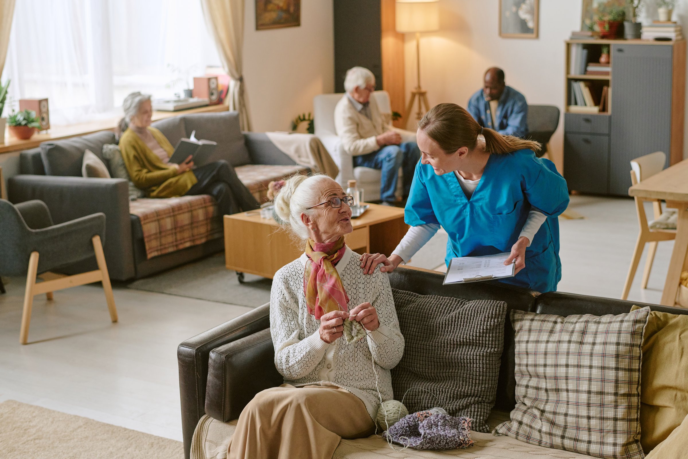High angle shot of nurse communicating with senior woman who sharing progress in crocheting