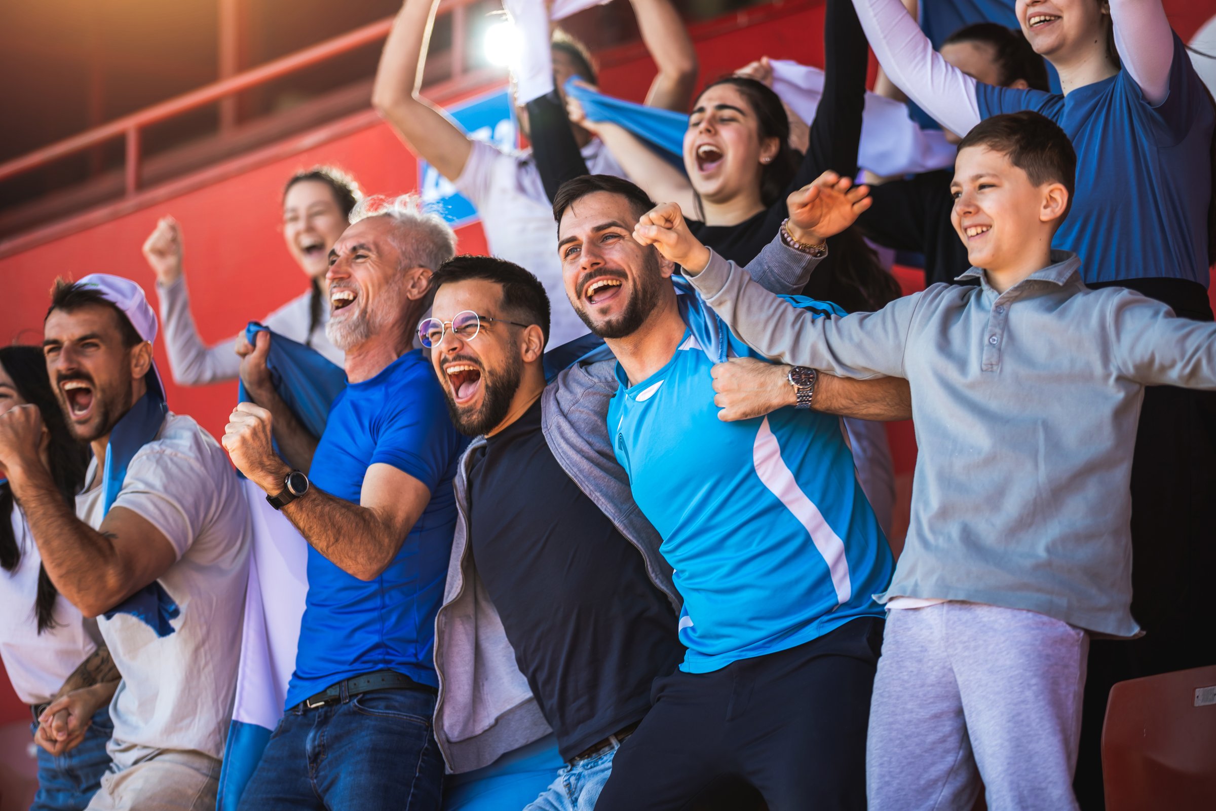 Football or soccer fans are cheering for their team at the stadium on the match
