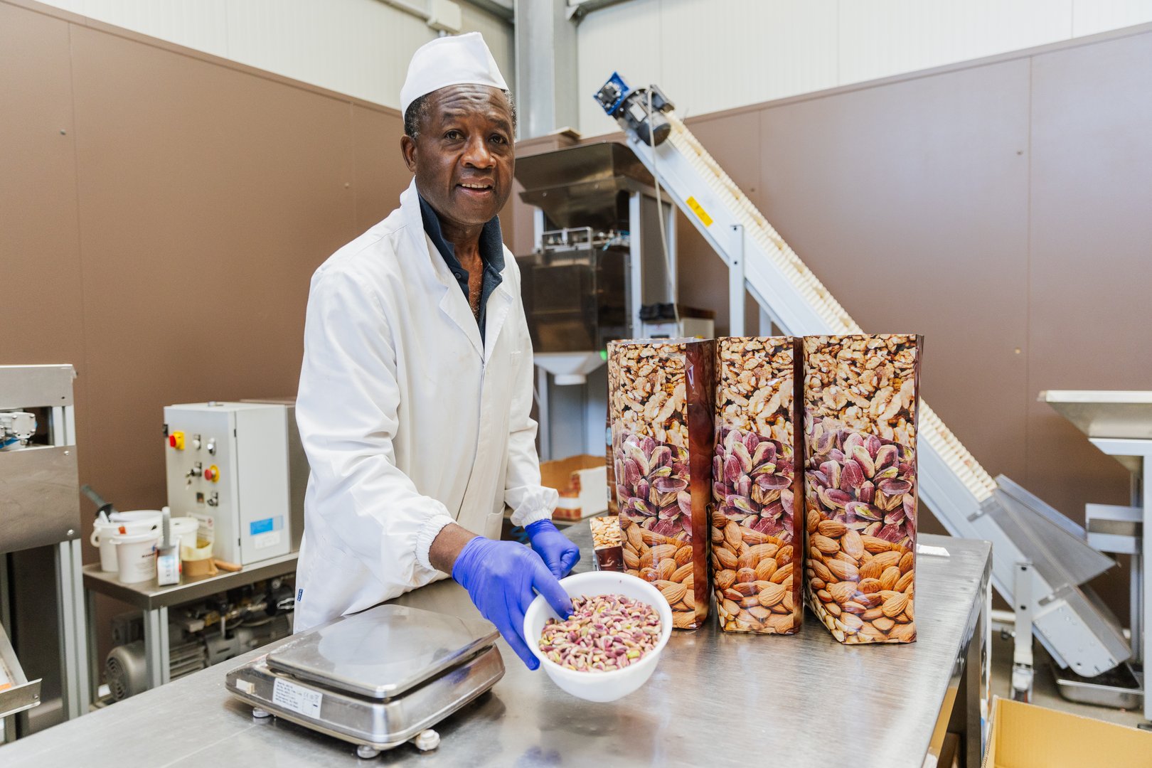 Warehouse worker weighing and packaging pistachios in a food processing facility.