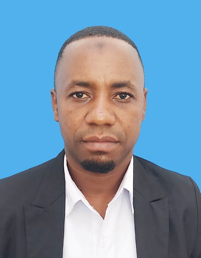 Portrait of a man in a black blazer and white shirt against a blue background, looking directly at the camera.