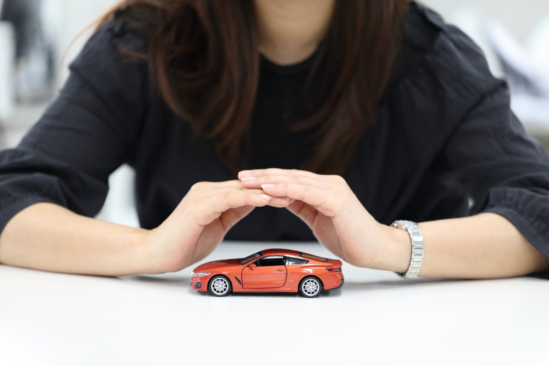 Hands protecting a car model