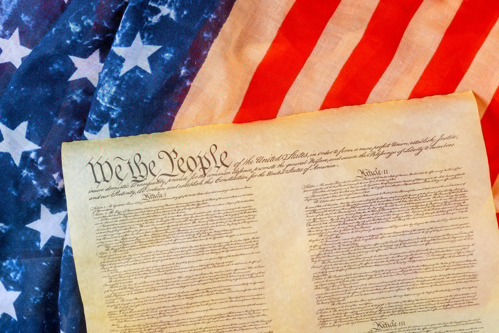 U.S. Constitution on an American flag symbolizes nation history, democracy, freedom.
