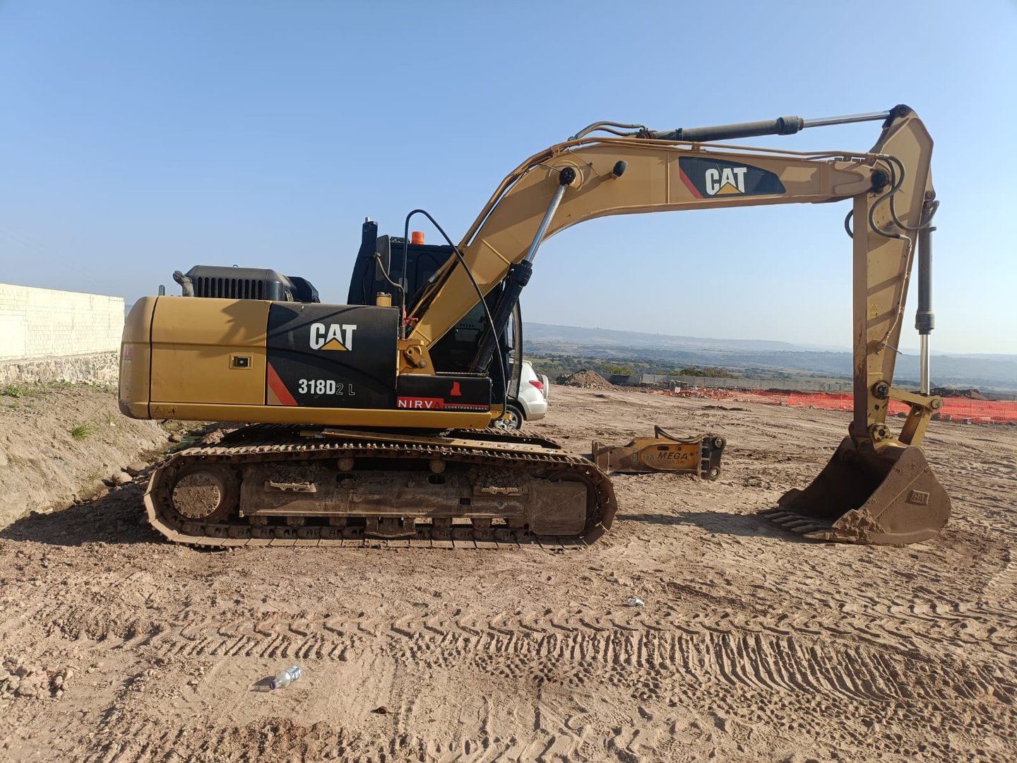 Excavator on a dirt construction site with a clear sky in the background.