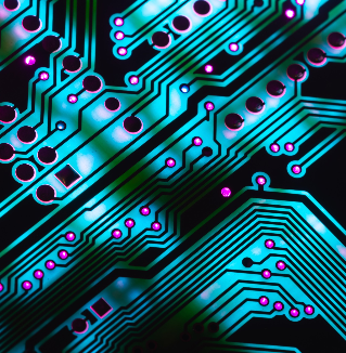 A highly magnified and brightly colored image of a computer circuit board, showing neon teal and pink traces and components.