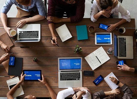 photo of a team collaborating with tablets and laptops around a table