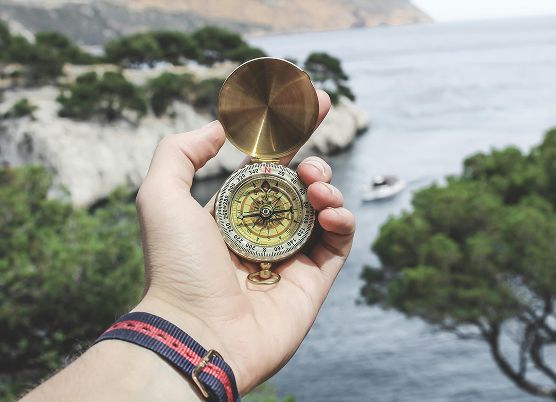 photo of a person holding a compass in the great outdoors