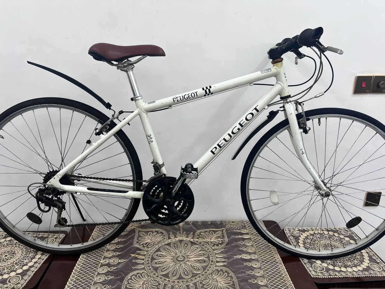 للبيع دراجة هوائية ​الماركة: بيجو (Peugeot).  
​الفئة: دراجة هجين / للمدينة (Hybrid / Fitness Bike). تدمج بين خفة دراجات الطريق ومقود وجلسة الدراجات الرياضية المريحة.
​2. الحجم والقياسات (Size):
​حجم الإطارات (العجلات): 28 إنش (قياس 700c القياسي للدراجات الهجين والتورنج) مع إطارات رفيعة مخصصة للشوارع والمشي السريع.
​حجم الهيكل (Frame Size): هيكل متوسط (Medium)، يناسب غالباً أطوال القامة بين 165 سم إلى 178 سم.
​3. المواصفات الفنية (Specifications):
​مادة الهيكل: ألمنيوم (Aluminium) خفيف الوزن ومقاوم للصدأ، مع وجود لحامات واضحة ومتقنة عند الوصلات.  
​نظام السرعات (الناقل):
​مبدلات سرعة وشغالات من شركة Shimano اليابانية.  
​تحتوي على 3 أقراص أمامية (دشالي) و6 إلى 7 تروس خلفية، مما يعطي 18 إلى 21 سرعة مختلفة للتنقل بين المرتفعات والسرعة على الطرق المستوية.
السعر 140وبي مجال للشراي مكاني بغداد تلفون ***********
