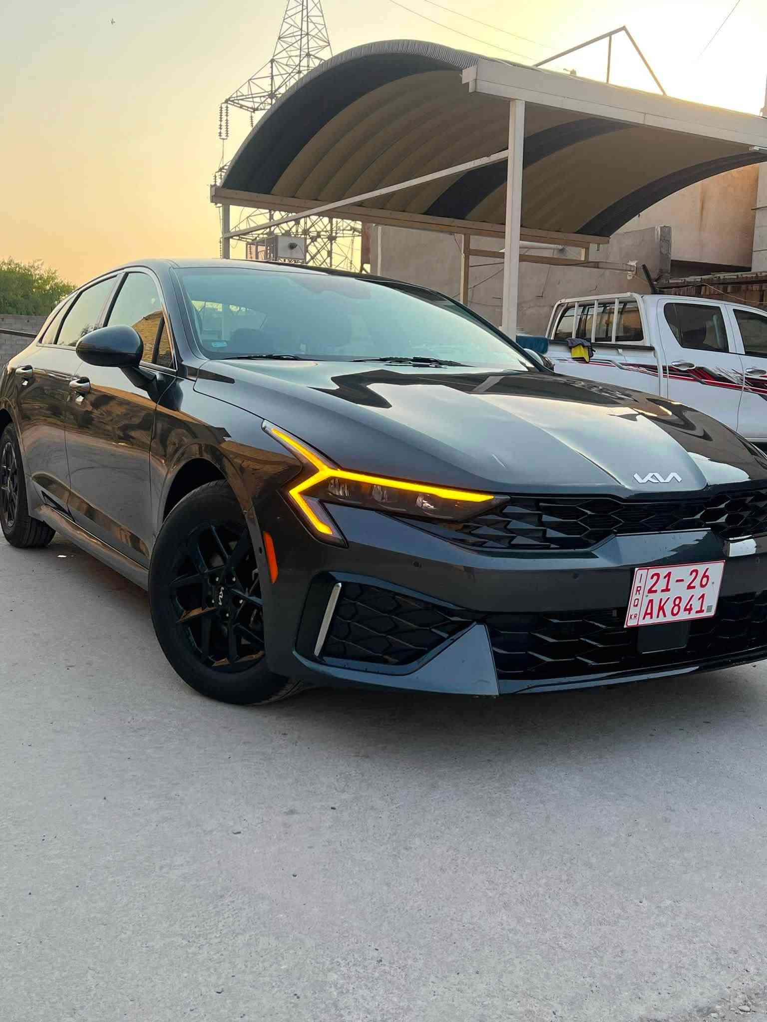 *مواصفات كيا K5 2024 EX*
*التفاصيل الاساسية:*
- *الموديل*: كيا K5 2024
- *الفئة*: EX
- *اللون*: رمادي غامق خارجي - اسود داخلي
- *الويل*: 18 انج اسود
- *الرقم*: اربيل
- *الوارد*: امريكي

*المواصفات الخارجية:*
- شباك امامي كروم اسود "Tiger Nose"
- لايتات LED امامية بتوقيع حرف Z
- لايتات خلفية LED متصلة بعرض السيارة
- حساسات خلفية + كاميرا رجوع
- مرايات جانبية اشاير + طي كهربائي
- دفيوزر خلفي بسيط

*المواصفات الداخلية اللي باينة بالصور:*
- *شاشتين متصلة 12.3"* Panoramic Display - عدادات ديجيتال + شاشة وسط
- *كاربلاي وايرلس* + اندرويد اوتو - باين بالصورة شغال خرائط
- *الداخلية*: قماش × جلد اسود
- *الستيرن*: جلد + تحكم متعدد + مثبت سرعة
- *الكير*: اوتوماتيك 8 سرعات
- *التبريد*: دبل زون ديجيتال لمس
- *ميزات*: بصمة تشغيل - تشغيل عن بعد - مثبت سرعة

*المحرك:*
- *المحرك*: 4 سلندر 2.5L GDI تنفس طبيعي 191 حصان
- *الكير*: 8 سرعات اوتوماتيك
- *الدفع*: امامي 2WD
- *انظمة القيادة*: Eco - Smart - Sport - Comfort

*الامان:*
- 6 ايرباك
- نظام الثبات + مانع انزلاق
- كاميرا رجوع + حساسات
- تنبيه الخروج من المسار على الاغلب
الحادث صبغ نص الباب والجاملغ الخلفي بارد

‭***********
