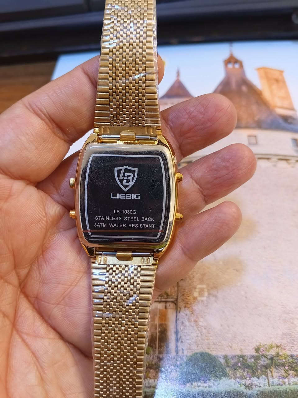 الماركة: LIEBIG [1]
رقم الموديل: LB-1030G (أو L1030) [1, 2]

الخامة: غطاء خلفي من الفولاذ المقاوم للصدأ (Stainless Steel Back) [1]

مقاومة الماء: مقاومة للماء حتى 3 أتموسفير (3ATM / 30 متر)، مما يعني أنها تتحمل رذاذ الماء الخفيف ولا تُلائم السباحة [1]

نوع الحركة: غالباً ما تكون ساعة كوارتز بتصميم مربع تجمع بين العرض الرقمي والتناظري [1]

ساعة سعرها 40 الف

نص مكتوب في الصور:
- Amigo
- حونبيغ
- تحفة كلاسيكية
- فخامة التاريخ في تصميم عصري. ساعة ليبيغ.