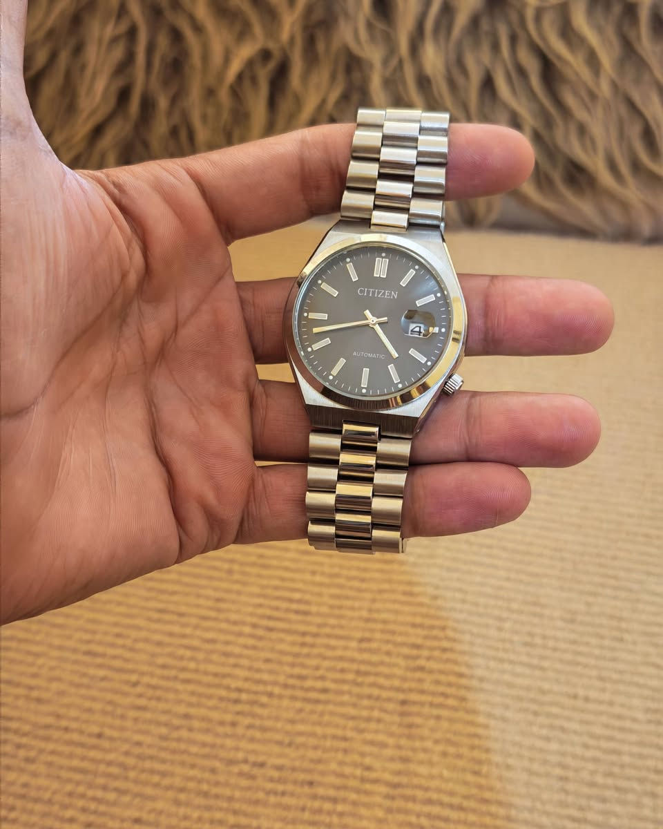 يا الله
ساعة سيتيزن (Citizen)، وتحديداً من مجموعة تسويوسا أوتوماتيك (Tsuyosa Automatic) الشهيرة.المواصفات الأساسية للساعة:نوع الحركة: أوتوماتيكية (تلقائية) تعمل بحركة المعصم.قطر العلبة: 40 ملم.مادة الصنع: فولاذ مقاوم للصدأ (ستانلس ستيل) للعلبة والسوار.تصميم المينا: مينا باللون الرمادي الداكن مع عقارب ومؤشرات ساعات ذات لمعان ذهبي أنيق.نافذة التاريخ: تقع عند مؤشر الساعة 3 مع عدسة مكبرة لقراءة التاريخ بسهولة.مقاومة الماء: مناسبة للاستخدام اليومي البسيط ورذاذ الماء (حتى عمق 50 متراً).
***********
