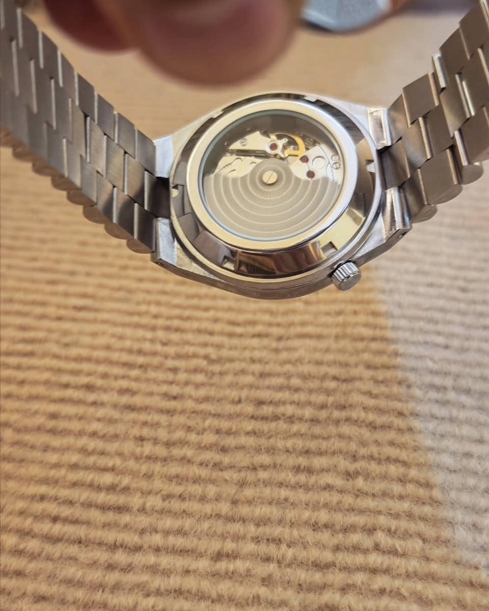 يا الله
ساعة سيتيزن (Citizen)، وتحديداً من مجموعة تسويوسا أوتوماتيك (Tsuyosa Automatic) الشهيرة.المواصفات الأساسية للساعة:نوع الحركة: أوتوماتيكية (تلقائية) تعمل بحركة المعصم.قطر العلبة: 40 ملم.مادة الصنع: فولاذ مقاوم للصدأ (ستانلس ستيل) للعلبة والسوار.تصميم المينا: مينا باللون الرمادي الداكن مع عقارب ومؤشرات ساعات ذات لمعان ذهبي أنيق.نافذة التاريخ: تقع عند مؤشر الساعة 3 مع عدسة مكبرة لقراءة التاريخ بسهولة.مقاومة الماء: مناسبة للاستخدام اليومي البسيط ورذاذ الماء (حتى عمق 50 متراً).
***********
