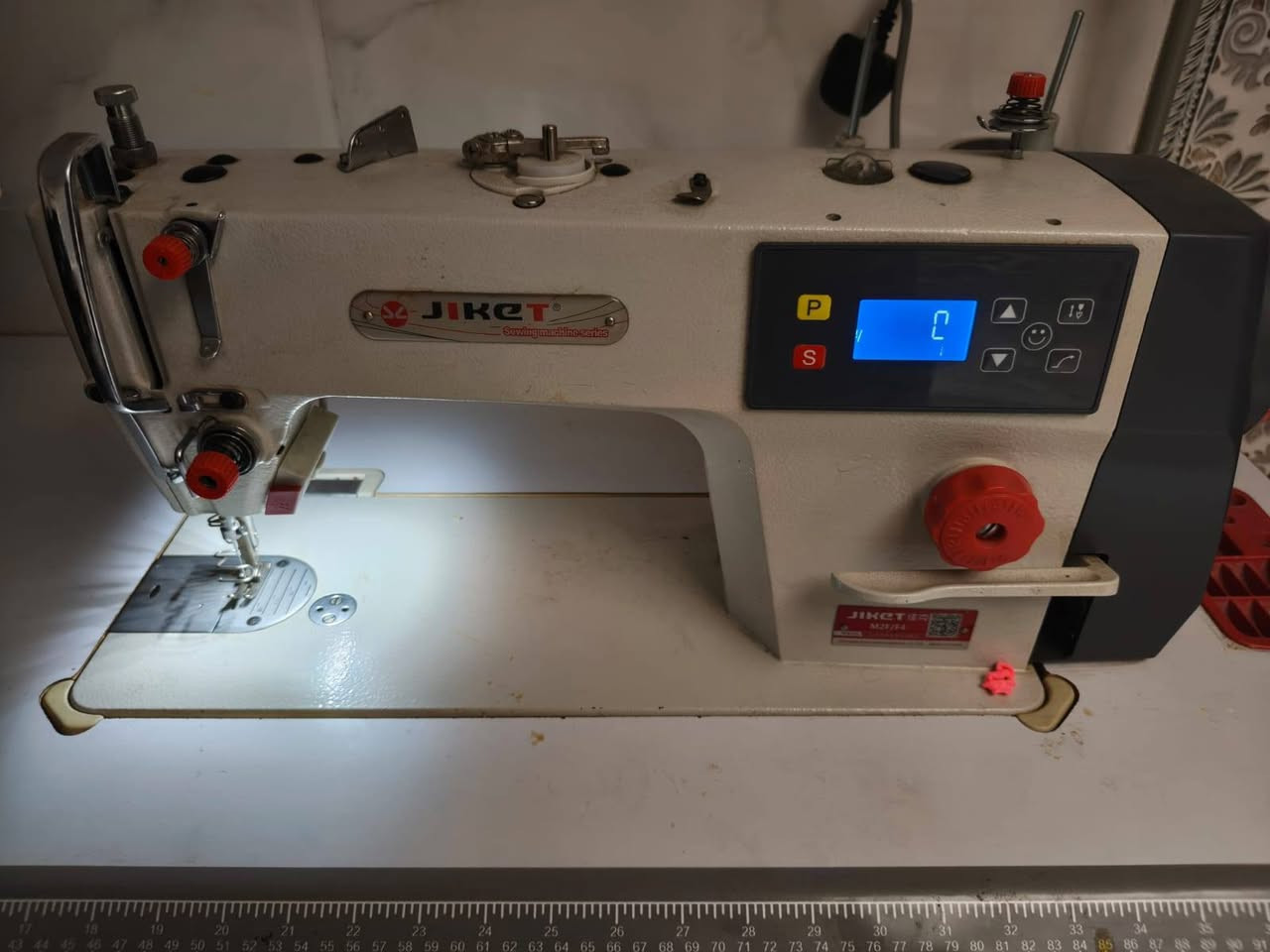 السلام عليكم 

هذه ماكينة خياطة صناعية درزة (Lockstitch) من شركة جاكيت (JIKET) موديل M2F (أو فئة M2 المتطورة بمحرك مباشر وسحب سريع).

⚙️ المواصفات والميزات الرئيسية:
محرك مباشر مدمج (Direct Drive): يوفر تشغيلاً صامتاً (كاتم للصوت) مع توفير كبير في استهلاك الطاقة مقارنة بالمحركات الخارجية التقليدية.

لوحة تحكم رقمية (شاشة رقمية): تتيح للمستخدم ضبط وتعديل خيارات التشغيل بسهولة، مثل التحكم بالسرعة (زيادة أو تقليل السرعة لتناسب مهارة الخياط ونوع القماش)

.منظم طول الغرزة الميكانيكي: البكرة الحمراء الكبيرة في الواجهة مخصصة لتعديل طول مسافة الغرزة بدقة.إضاءة LED مدمجة: مصباح مدمج عند منطقة الإبرة لتسهيل الرؤية وتخفيف إجهاد العين أثناء العمل

.نظام تزييت أوتوماتيكي: مضخة زيت داخلية تضمن تشحيم كافة الأجزاء الميكانيكية تلقائياً لتقليل الاحتكاك وزيادة العمر الافتراضي للماكينة.

استعمال قليل جداً السعر (350 الف) وبيه مجال قليل 
عنواني بغداد الحسينية مدخل الحمل 
*********** واتساب او تصال
