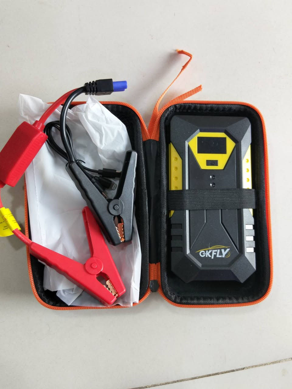 السعر 45 الف
هذا الجهاز هو مشغل طوارئ لبطارية السيارة (Car Jump Starter) وتعمل كبنك طاقة محمول (Power Bank) متعدّد الوظائف من ماركة GKFLY، وتتلخص آلية عمله ووظائفه الرئيسية في النقاط التالية:
​1. تشغيل السيارة عند تفريغ البطارية (Jump Start)
​كيف يعمل: يزود محرك السيارة بتيار كهربائي عالٍ ومفاجئ لتشغيلها مباشرة في حال كانت البطارية فارغة أو ضعيفة، دون الحاجة لسيارة أخرى.
​طريقة الاستخدام:
​صِل القابس الأزرق الخاص بكابل المشابك بالمنفذ المخصص له في الجهاز.
​صِل المشبك الأحمر بالقطب الموجب (+) لبطارية السيارة.
​صِل المشبك الأسود بالقطب السالب (-) لبطارية السيارة.
​شغّل الجهاز ثم قم بتشغيل سلف السيارة.
​2. بنك طاقة لشحن الأجهزة الإلكترونية (Power Bank)
​يحتوي على منافذ USB لشحن الهواتف المحمولة والأجهزة اللوحية.
​تدعم الشاشة إظهار جهود خروج متعددة (مثل 5V, 9V, 12V, 16V, 19V) لشحن أجهزة متنوعة مثل الهواتف وبعض أجهزة اللابتوب أو الكاميرات.
​3. إضاءة كشاف طوارئ (LED Light)
​يحتوي على مصابيح LED في الجانب تُستخدم للإضاءة أثناء الليل أو في حالات الطوارئ على الطريق، مع أنماط إضاءة مختلفة (إضاءة مستمرة، فلاش SOS للطوارئ).
​4. شاشة عرض الرقمية (LCD Display)
​تعرض الشاشة نسبة شحن الجهاز المتبقية (100% - 0%)، بالإضافة إلى حالة الشحن والجهد المستخدم (IN / OUT).
***********
