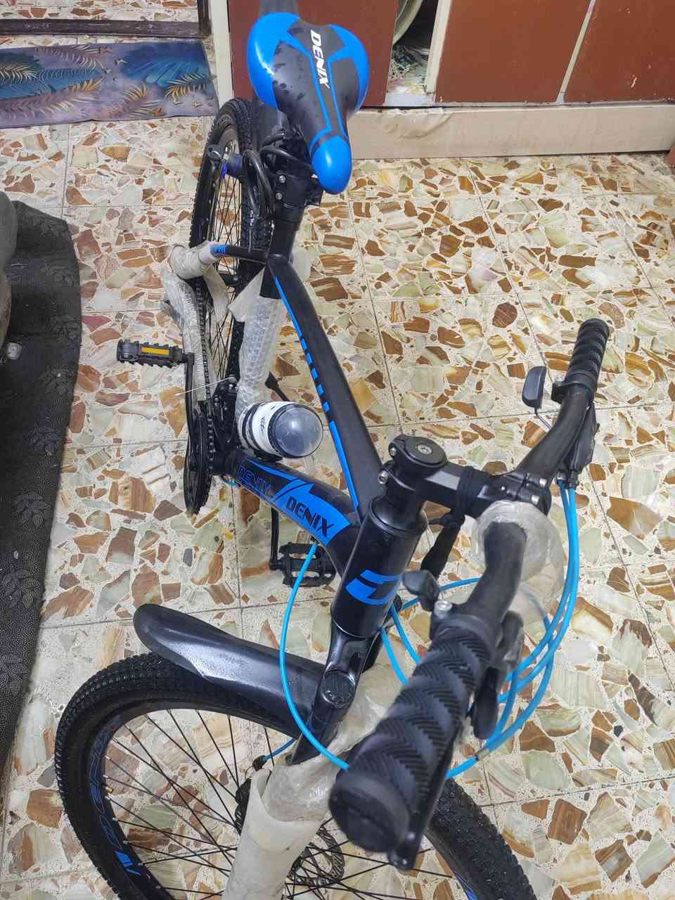 سلام عليكم بايسكل DENIX جبلي - للبيع 🚴‍♂️
​المواصفات والتفاصيل:
​الماركة: DENIX (أصلي).
​النوع: جبلي (Mountain Bike) مناسب للمشي اليومي وللطرق الوعرة.
​الحالة: جديد (مغلف بتغليف الشركة).
​اللون: أسود مع تطعيم أزرق مميز.
​نظام المكابح: ديسك (Disc Brakes) أمامي وخلفي لثبات وقوة توقف.
​المساعدات: دبل أمامي امتصاص صدمات لتنعيم القيادة.
​السرعات: نظام جيرات/دوشج متعدد السرعات تحكم كامل.
​الملحقات المرفقة:
​مطارة ماء مع القاعدة.
​قماريات (قاطعات طين) أمامي وخلفي.
​جك (ستاند) جانبي.
​كمر (سرج) رياضي مريح DENIX.
​📍 المكان: بغداد مدينه الصدر 
📞 للتواصل:  *********** 
💰 السعر:  190
